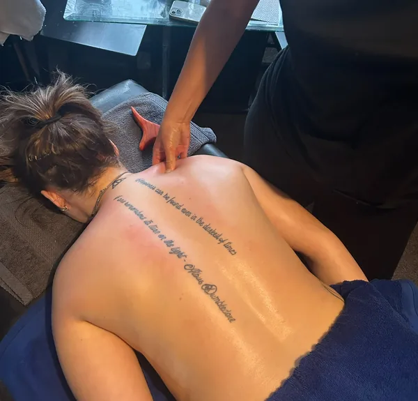 Focused thumb pressure applied to a client's upper back during a deep tissue treatment