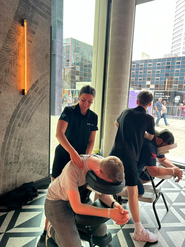 Seated chair massage delivered to workers in a glass-fronted city building