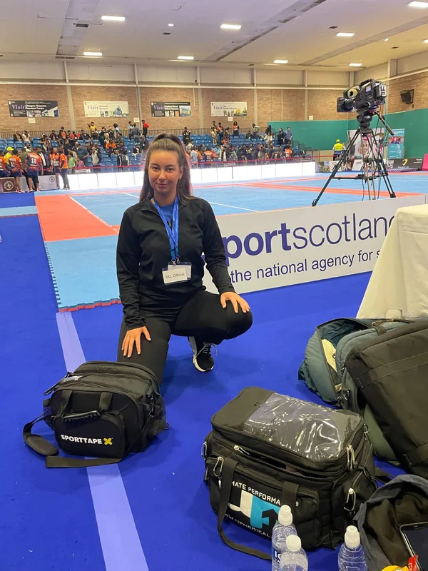 Mia kneeling beside her packed therapy kit bags on the Kabaddi mat before play