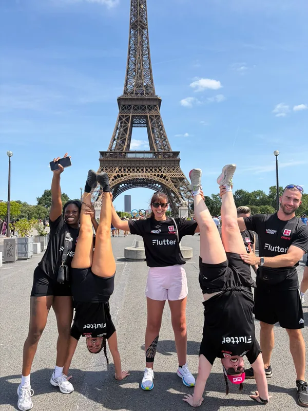 Support crew members doing handstands in front of the Eiffel Tower at the ride finish