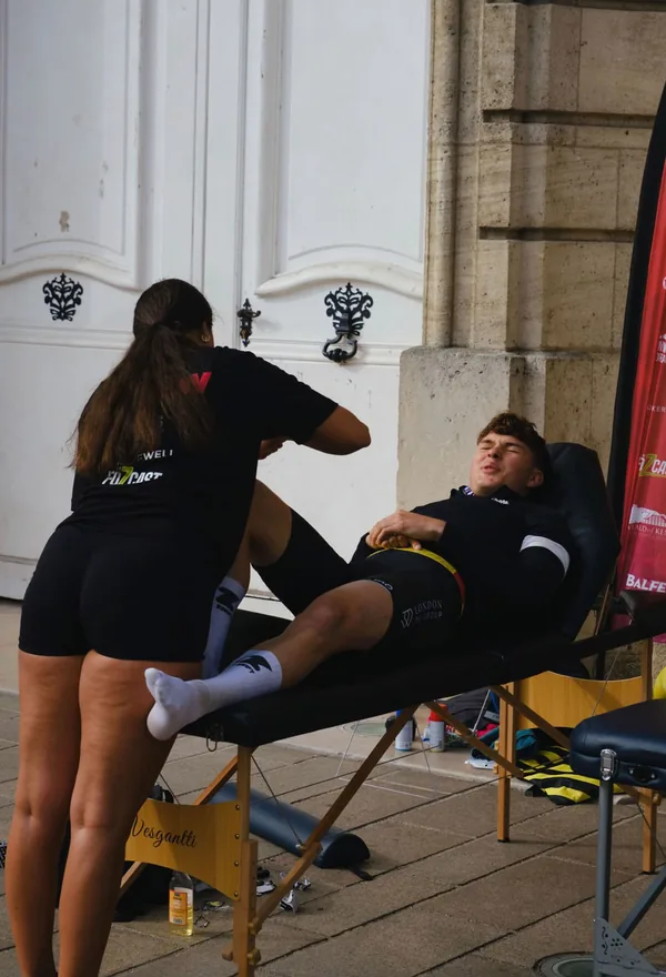 Mia taking a cyclist's leg through an assisted stretch on a treatment couch
