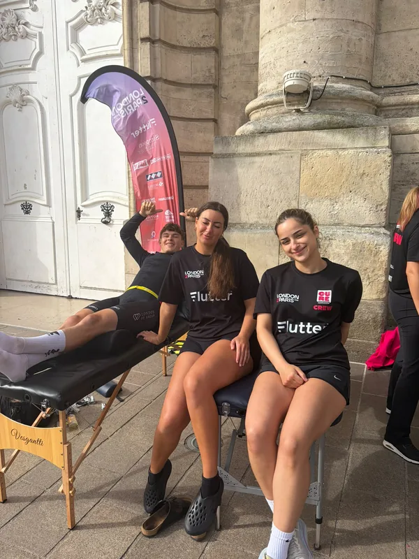Mia and a colleague sat on treatment couches in Cure Leukaemia crew shirts