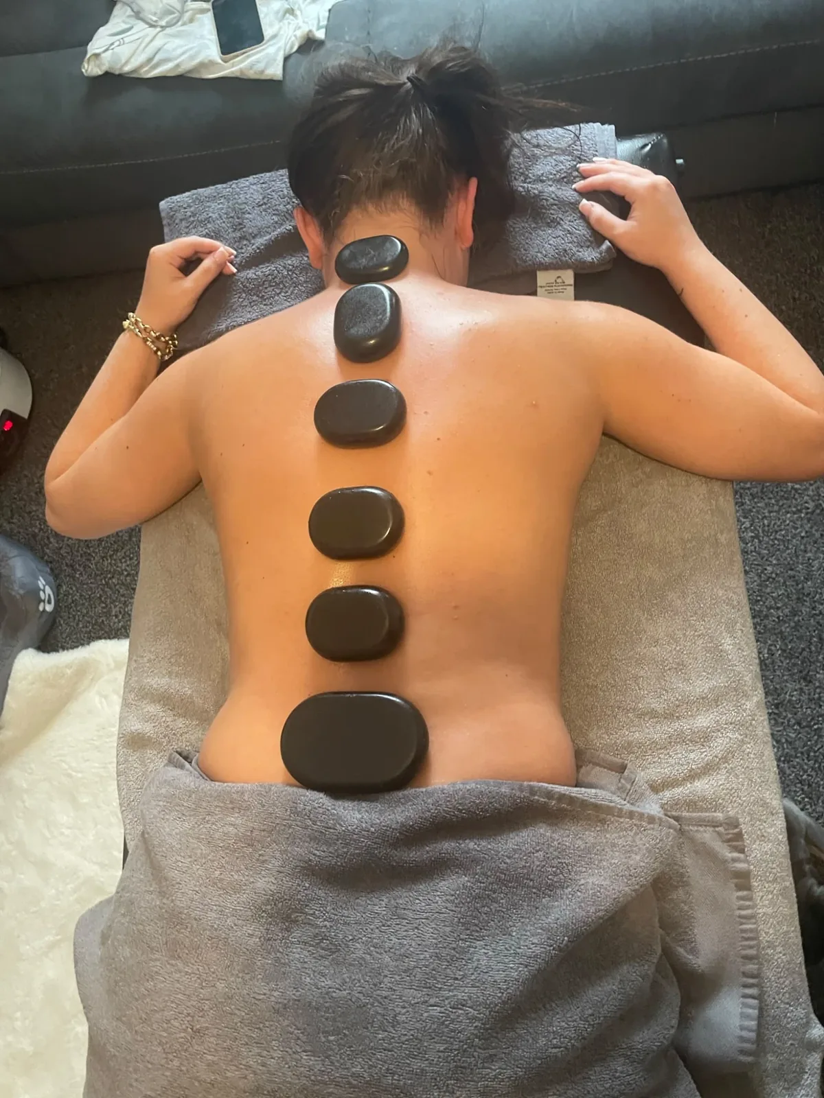 Heated basalt stones laid in a line along a client's spine during a hot stone massage