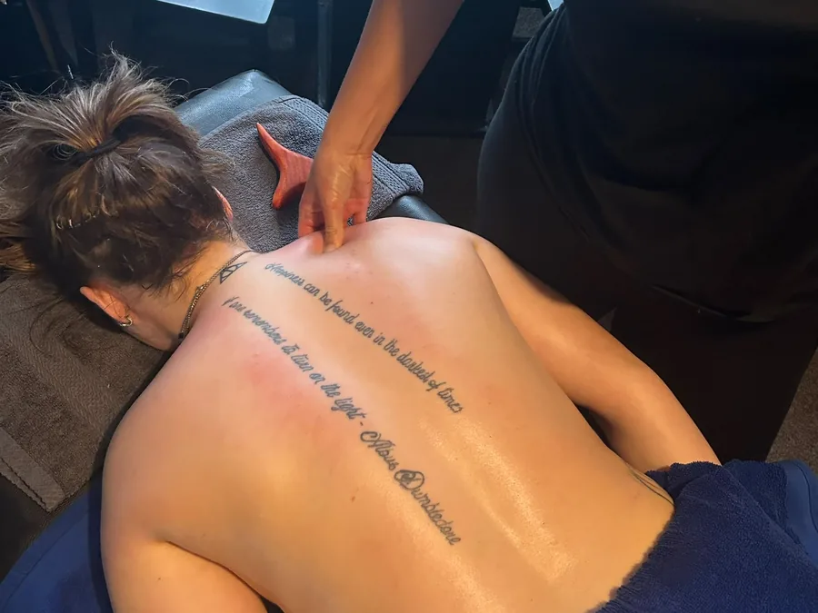 Close hands-on soft tissue work through a client's upper back on the treatment couch